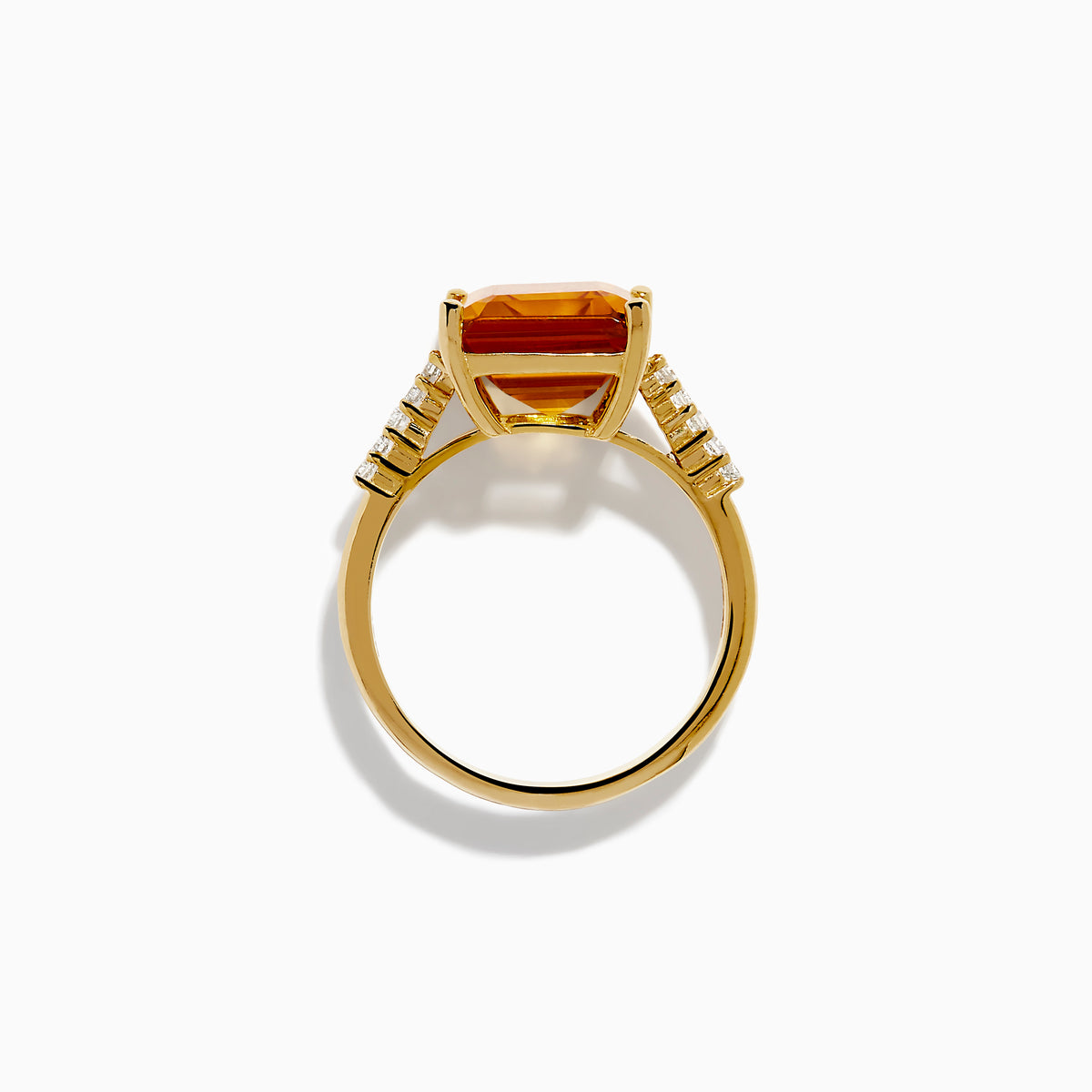 The 14K Yellow Gold Step Cut Citrine and Diamond Cocktail Ring features a large rectangular citrine centerpiece with small round diamonds set along the band on each side of the main stone.