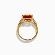 The 14K Yellow Gold Step Cut Citrine and Diamond Cocktail Ring features a large rectangular citrine centerpiece with small round diamonds set along the band on each side of the main stone.