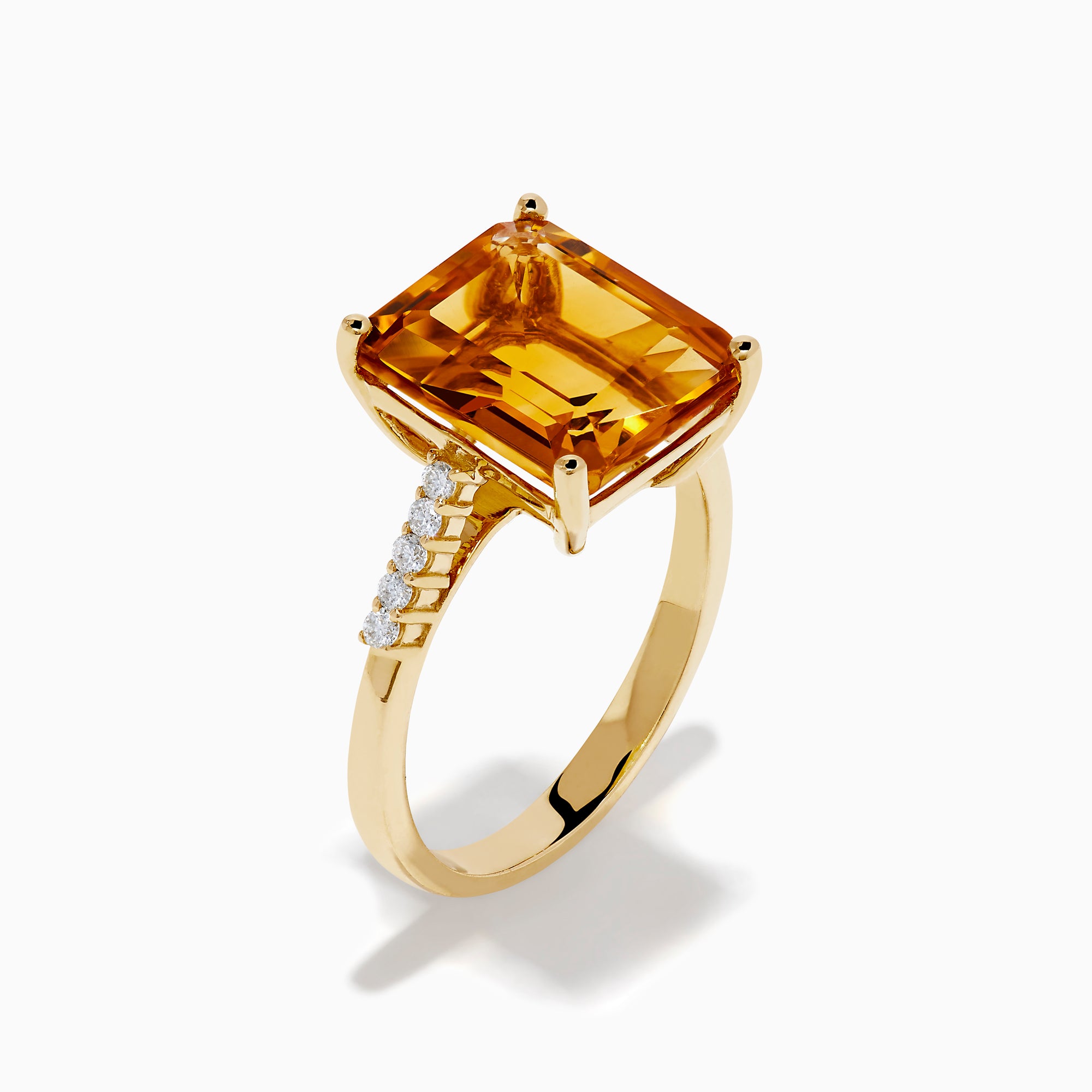 The 14K Yellow Gold Step Cut Citrine and Diamond Cocktail Ring features a large rectangular citrine centerpiece with small round diamonds set along the band on each side of the main stone.