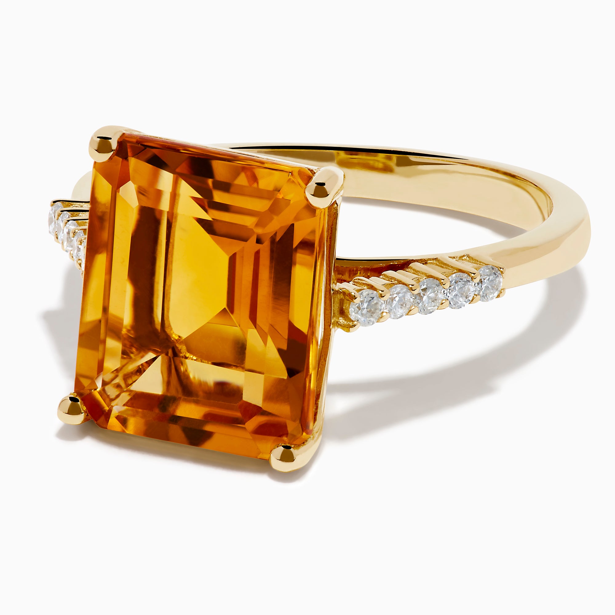The 14K Yellow Gold Step Cut Citrine and Diamond Cocktail Ring features a large rectangular citrine centerpiece with small round diamonds set along the band on each side of the main stone.