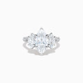 The Lab Grown Marquise Diamond 3 Stone Ring in 14K White Gold features a central marquise-cut lab grown diamond, two flanking marquise-cut diamonds, and two round diamonds set on a detailed band against a white background.