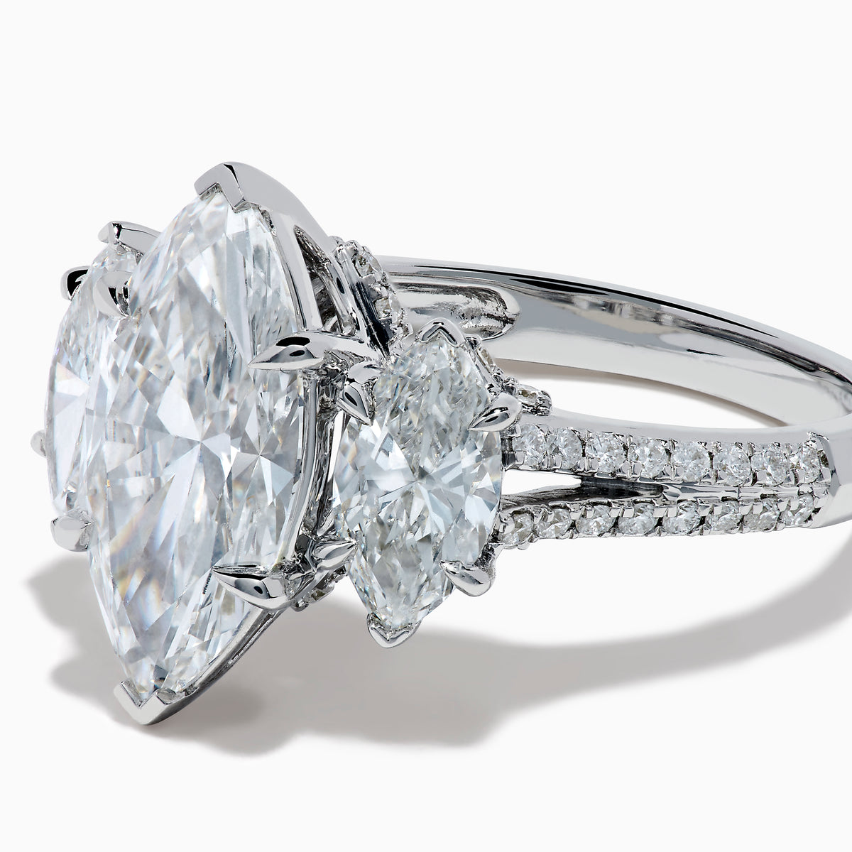 The Lab Grown Marquise Diamond 3 Stone Ring in 14K White Gold features a central marquise-cut lab grown diamond, two flanking marquise-cut diamonds, and two round diamonds set on a detailed band against a white background.