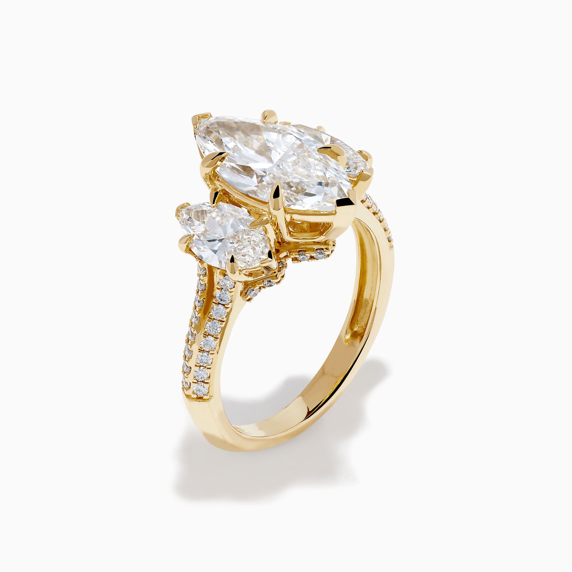 The Lab Grown Marquise Diamond 3 Stone Ring in 14K Yellow Gold features a central lab-grown marquise diamond, flanked by two pear-shaped diamonds with additional smaller stones adorning the band, shown on a white background.