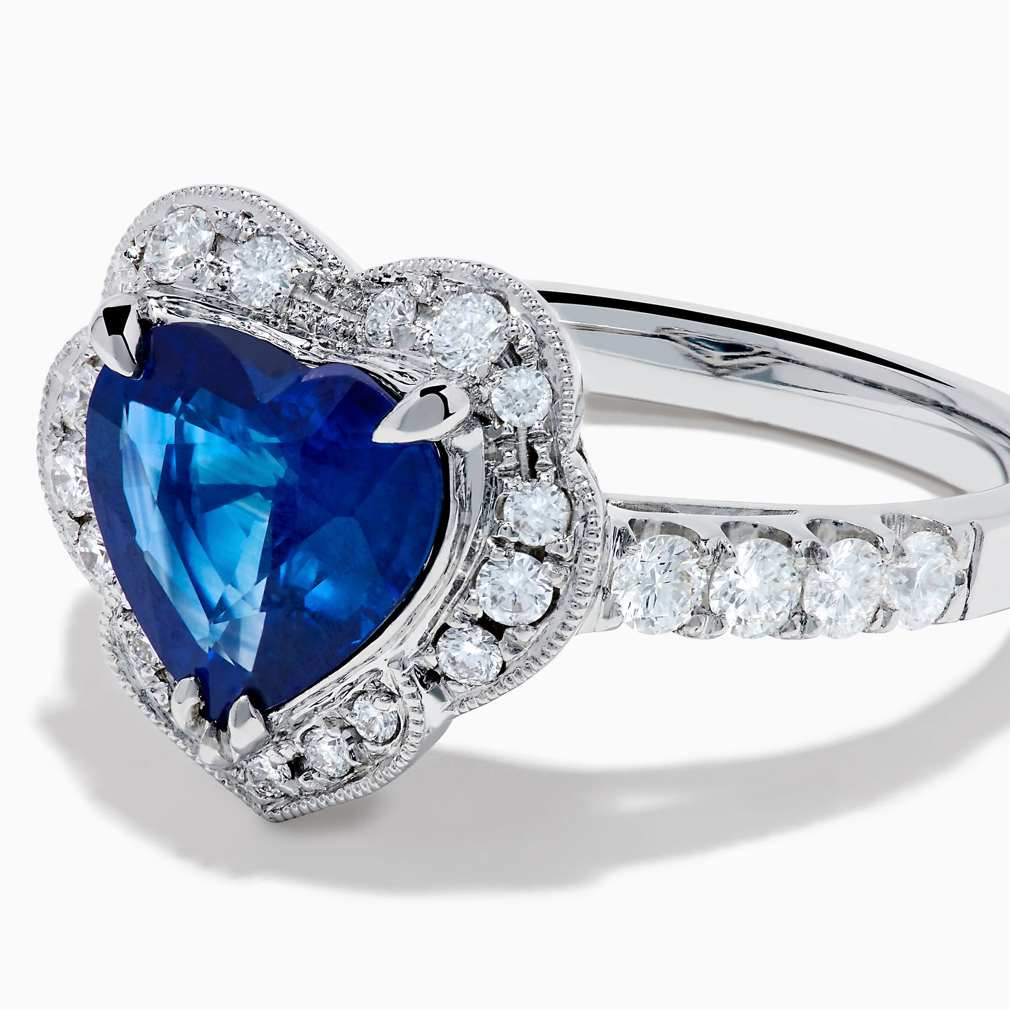 The Effy Hematian 18K White Gold Heart Shaped Blue Sapphire and Diamond Halo Ring features a heart-shaped blue sapphire center stone, a diamond halo, and additional diamonds along the band.
