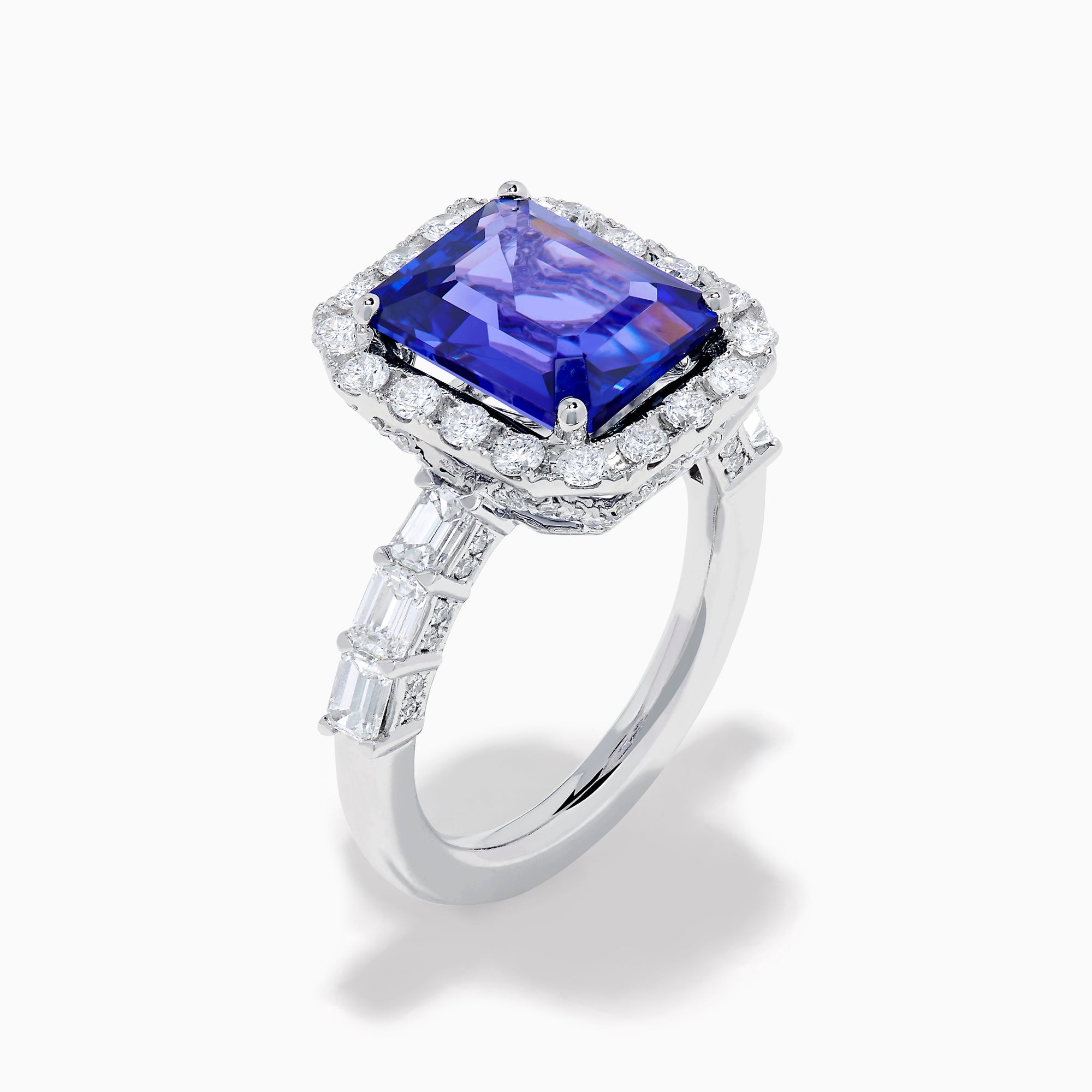 The Effy Hematian 18K White Gold Tanzanite and Diamond Halo Ring showcases a large rectangular blue tanzanite at the center, encircled by a diamond halo with additional diamonds set along the band.