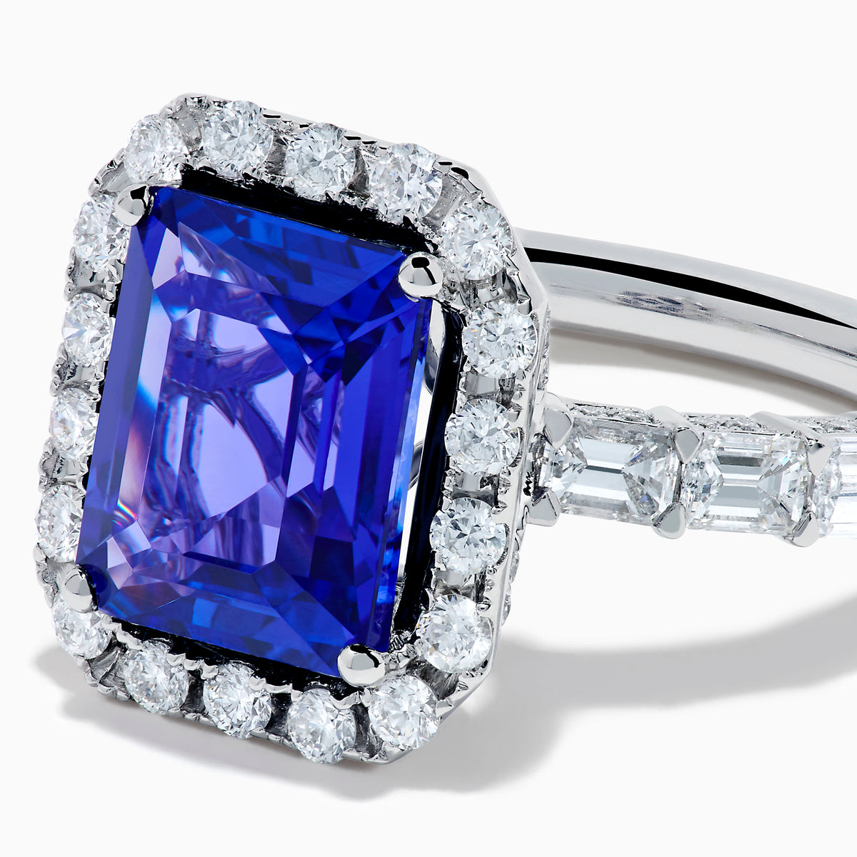 The Effy Hematian 18K White Gold Tanzanite and Diamond Halo Ring showcases a large rectangular blue tanzanite at the center, encircled by a diamond halo with additional diamonds set along the band.