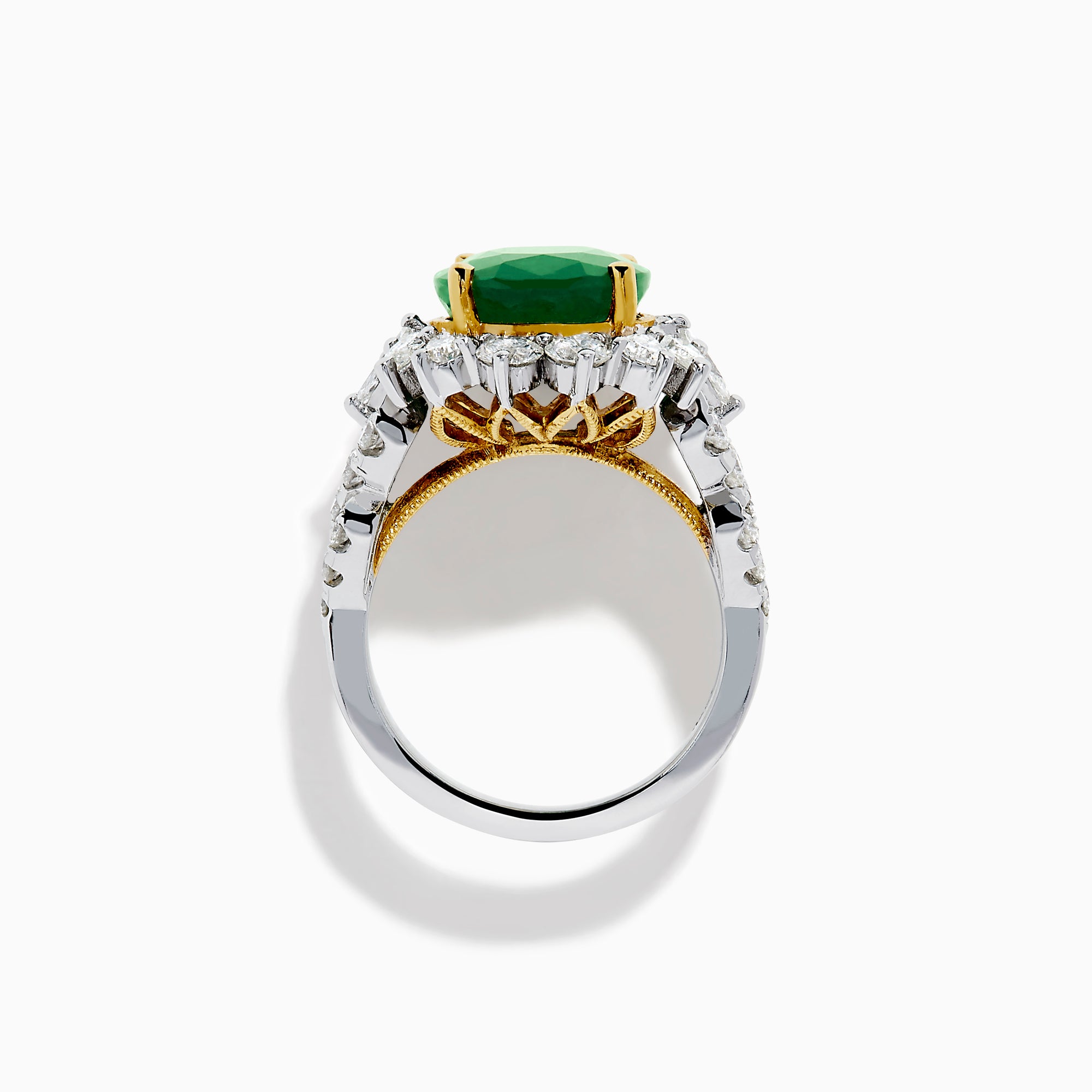 The 18K Two-Tone Gold Emerald, Yellow and White Diamond Ring features a striking oval green emerald surrounded by white diamonds, set in a gold and silver band with gold prongs, shown against a plain white background.
