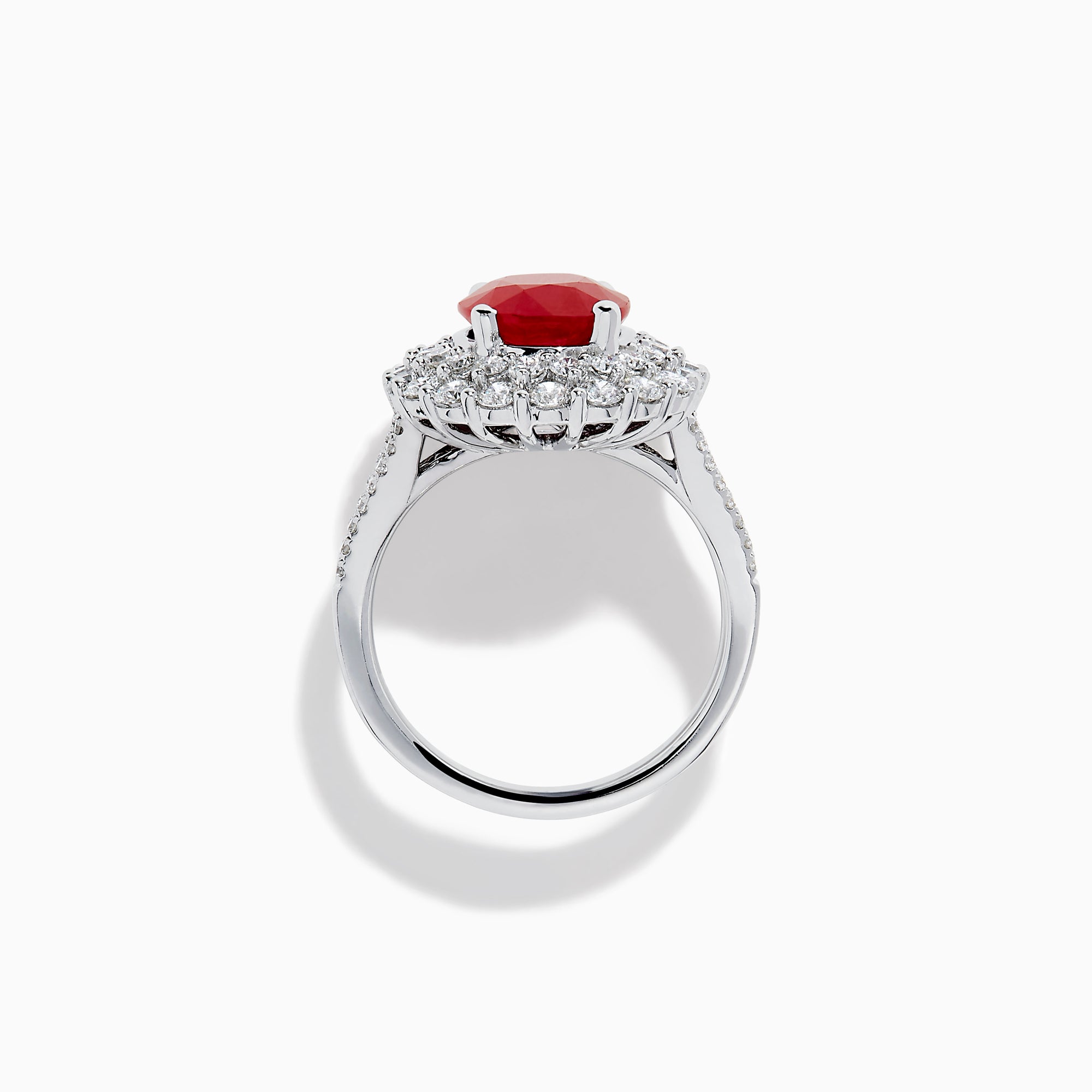 The 18K White Gold Ruby and Diamond Double Halo Ring features an oval ruby encircled by double diamond halos on a sleek white gold band, showcased against a white background.