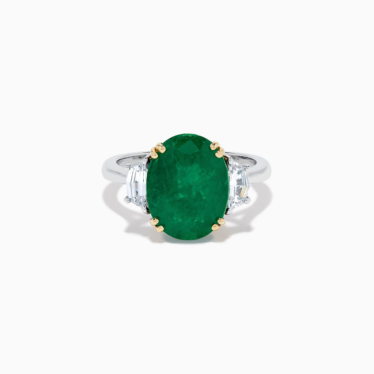 The Effy Hematian 14K Two Tone Gold Emerald and Diamond Three-Stone Ring features a large oval emerald center set with four gold prongs, flanked by two clear rectangular diamonds on a gold and silver band.
