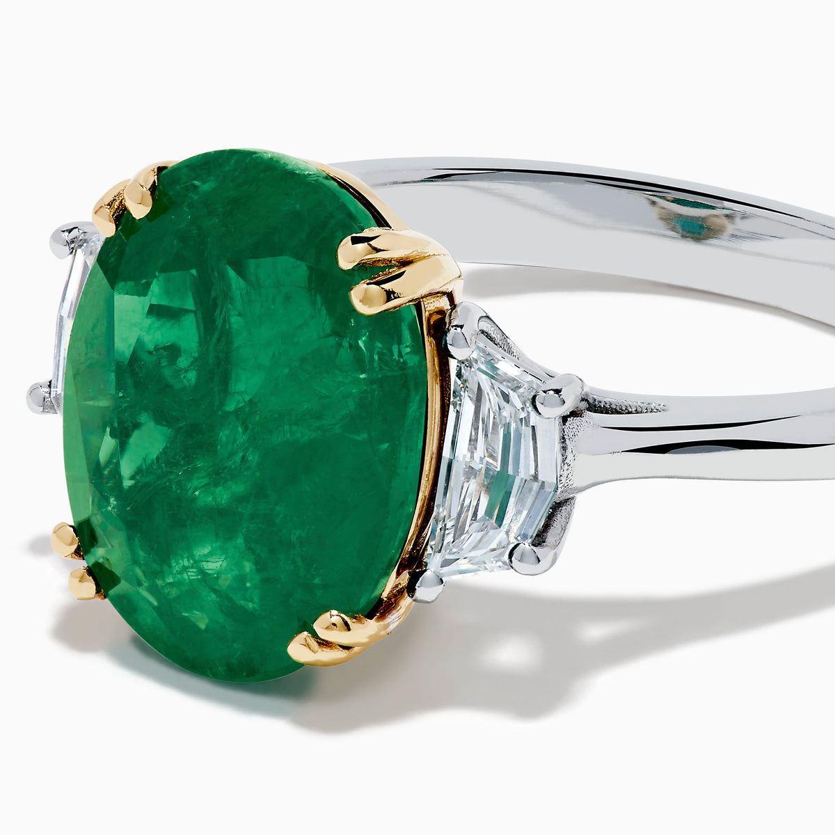 The Effy Hematian 14K Two Tone Gold Emerald and Diamond Three-Stone Ring features a large oval emerald center set with four gold prongs, flanked by two clear rectangular diamonds on a gold and silver band.