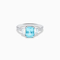 The Effy Hematian 18K White Gold Paraiba Tourmaline and Diamond Ring showcases a vibrant, large rectangular tourmaline center stone, flanked by two side diamonds and a band adorned with small round diamonds.