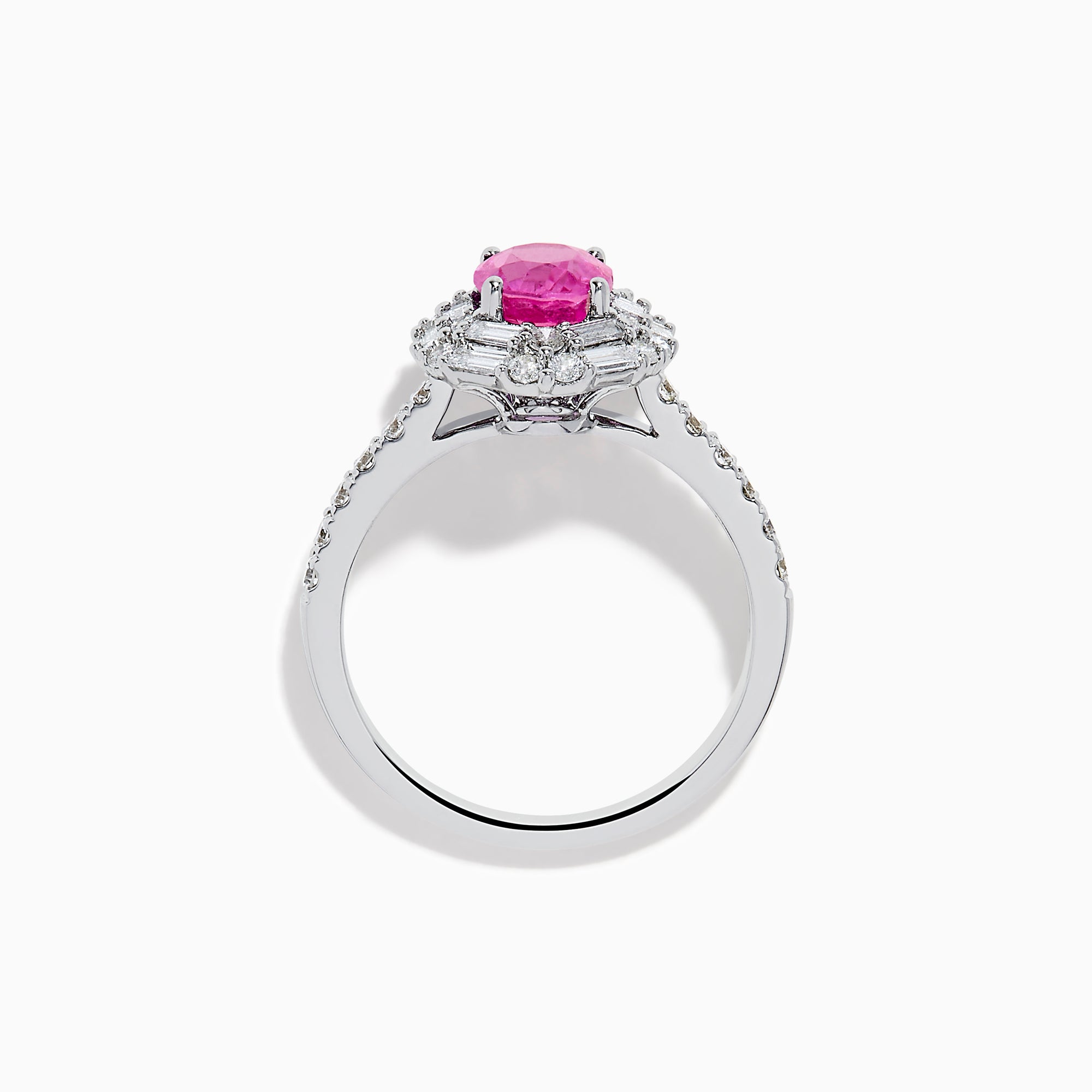 The 18K White Gold Pink Sapphire and Diamond Halo Ring showcases an oval pink sapphire center, encircled by a halo of baguette and round-cut diamonds, with more diamonds adorning the band.
