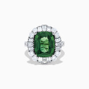 The 18K White Gold Green Sapphire and Diamond Halo Ring showcases a large oval green sapphire, surrounded by round and rectangular white diamonds, set on an elegant white gold band and displayed on a white background.