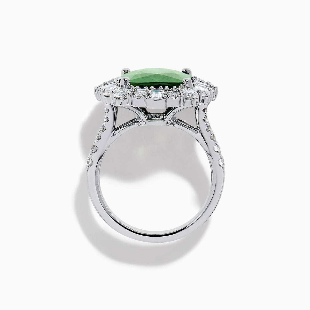 The 18K White Gold Green Sapphire and Diamond Halo Ring showcases a large oval green sapphire, surrounded by round and rectangular white diamonds, set on an elegant white gold band and displayed on a white background.