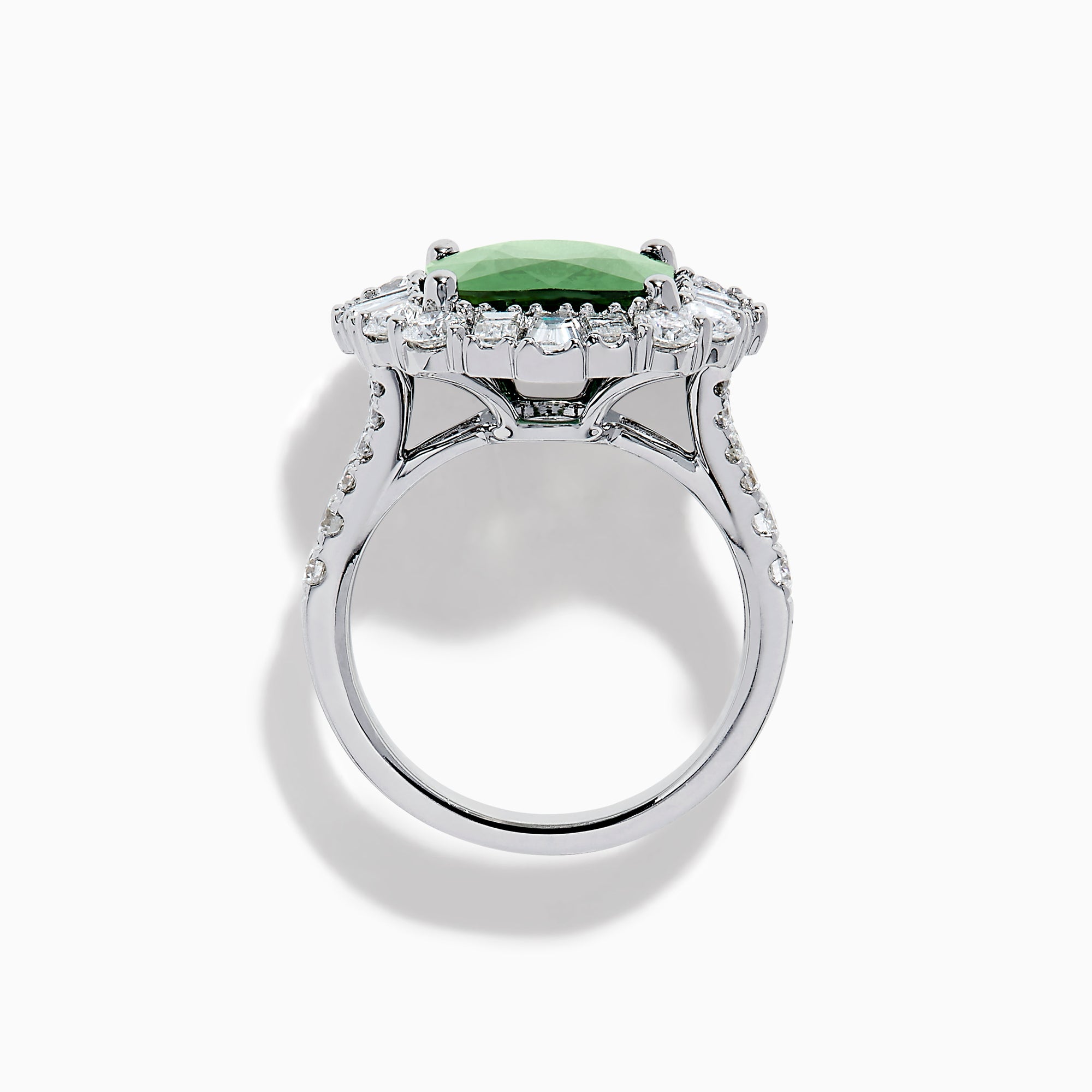 The 18K White Gold Green Sapphire and Diamond Halo Ring showcases a large oval green sapphire, surrounded by round and rectangular white diamonds, set on an elegant white gold band and displayed on a white background.