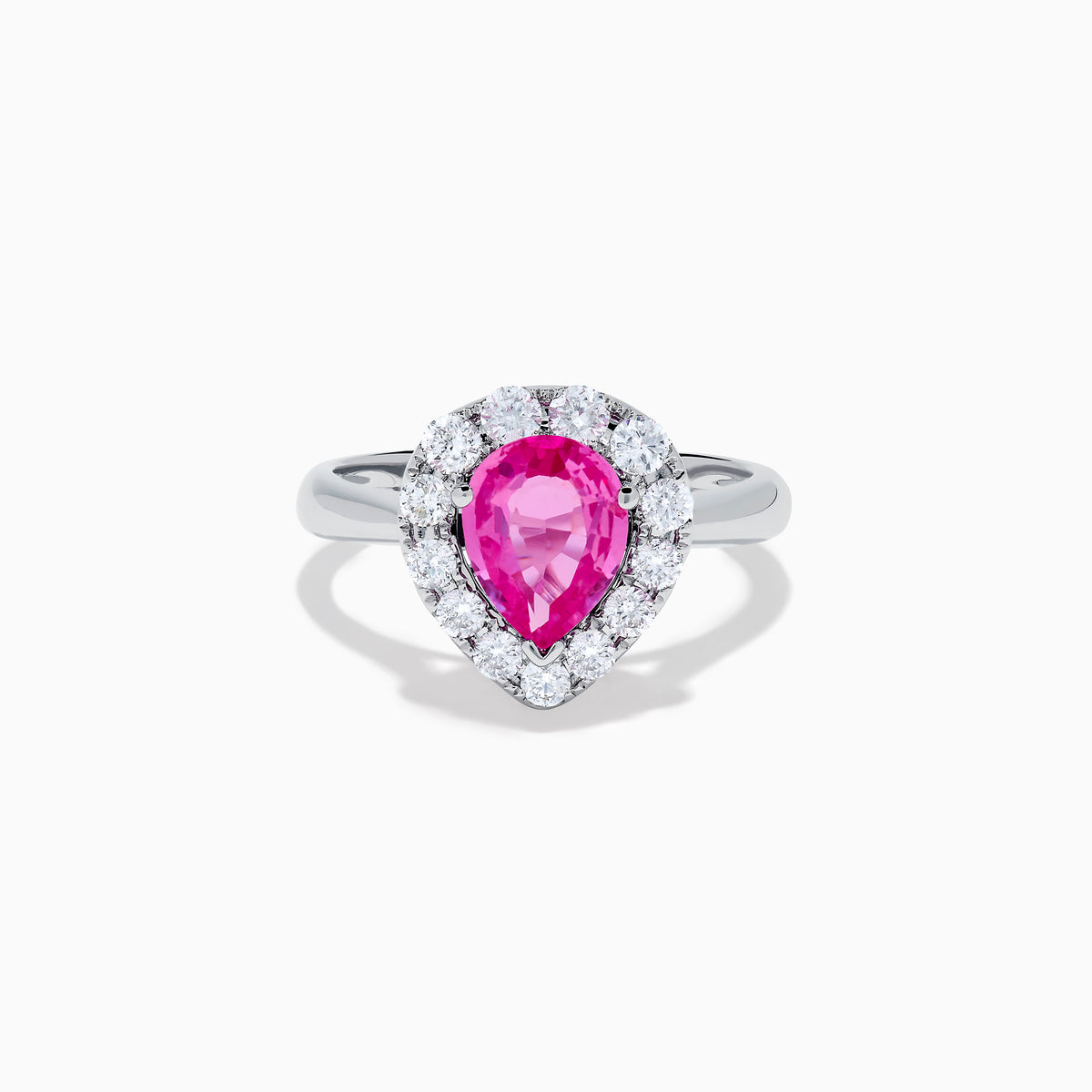 The 18K White Gold Pink Sapphire and Diamond Halo Ring features a pear-shaped pink sapphire center, accented by a sparkling diamond halo, elegantly displayed against a plain white background.