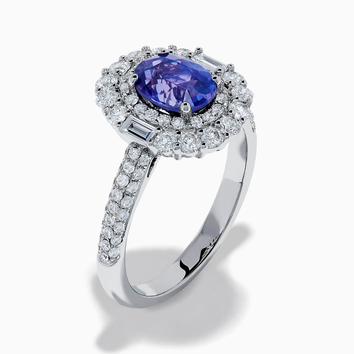 The 18K White Gold Purple Sapphire and Diamond Double Halo Ring features an oval purple sapphire center, two rows of white diamonds encircling it, and additional diamonds set along the band.