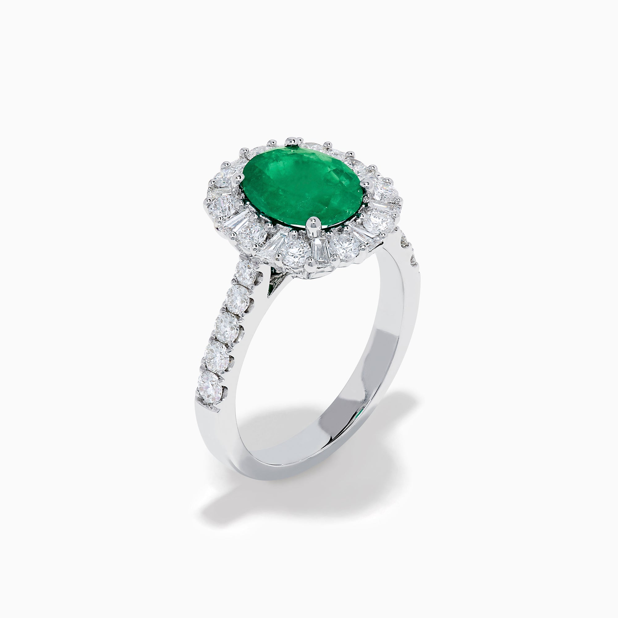 The Effy Hematian 18K White Gold Oval Emerald and Diamond Halo Ring features a vibrant oval emerald at the center, surrounded by a sparkling diamond halo with additional diamonds set along the elegant band.