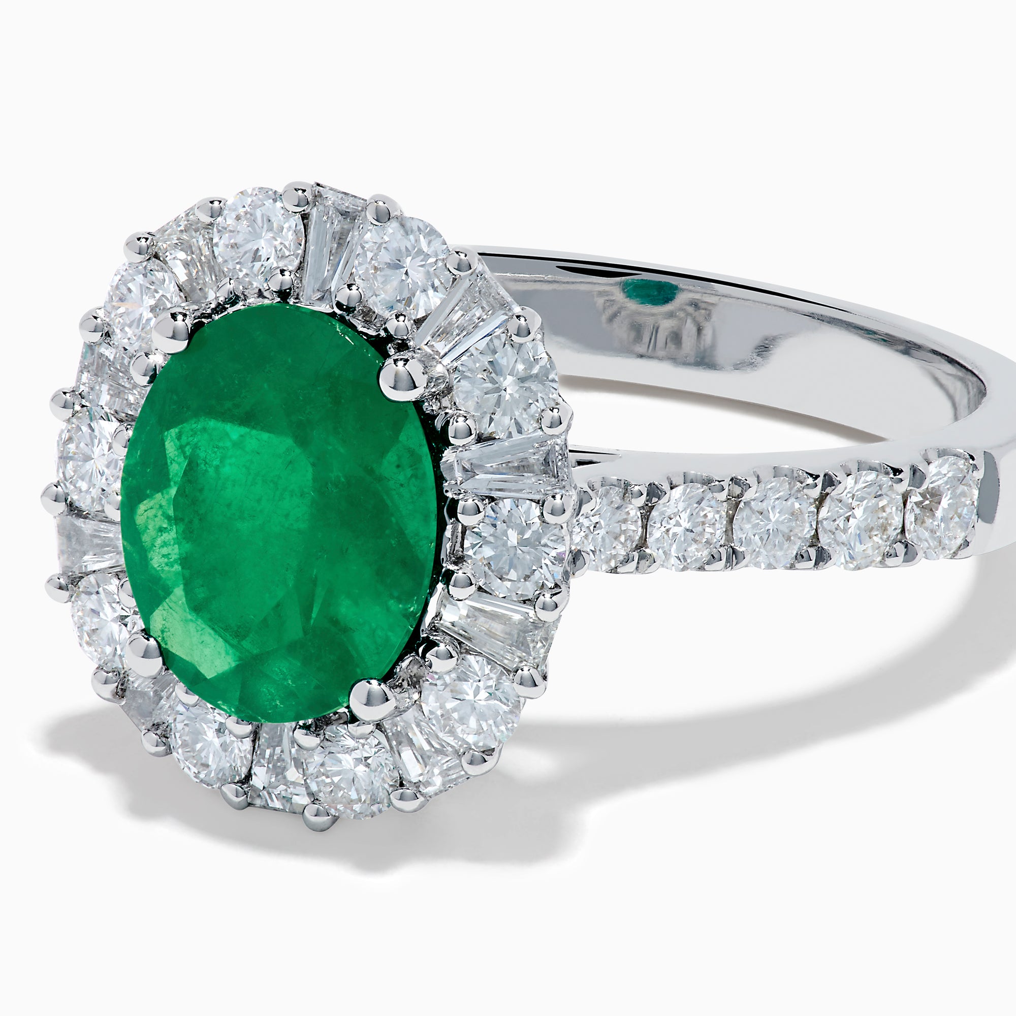 The Effy Hematian 18K White Gold Oval Emerald and Diamond Halo Ring features a vibrant oval emerald at the center, surrounded by a sparkling diamond halo with additional diamonds set along the elegant band.