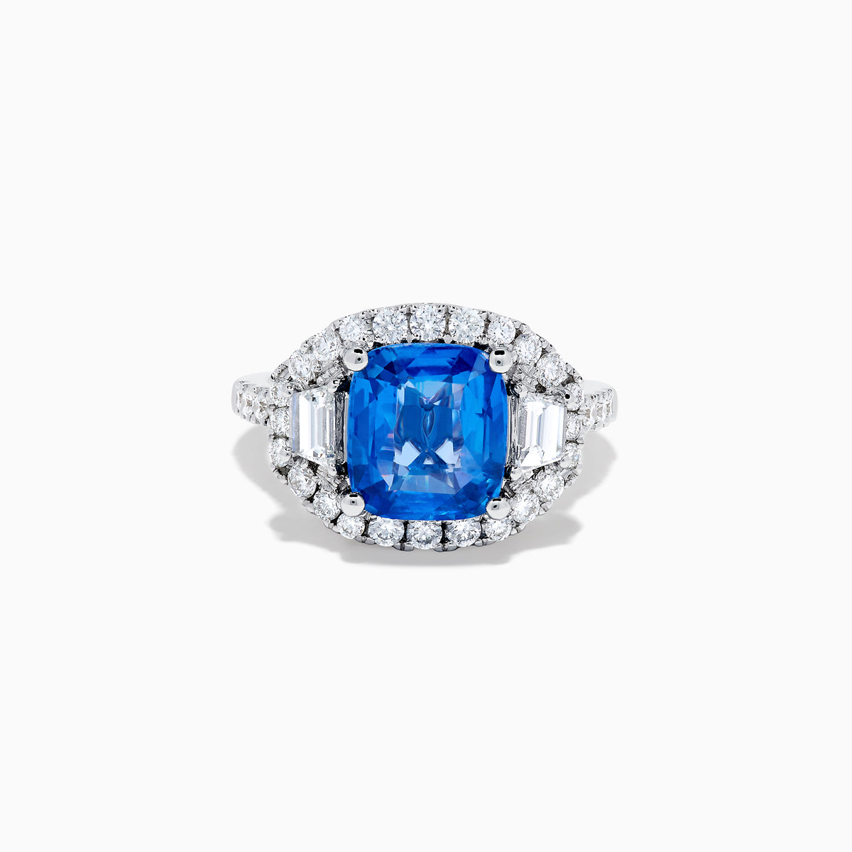 The Effy Hematian 18K Gold Cushion-Cut Blue Sapphire and Diamond Ring features a striking cushion-cut blue sapphire surrounded by a halo of round and baguette diamonds, all set in polished white 18K gold.