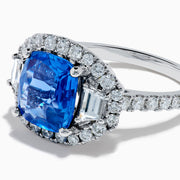 The Effy Hematian 18K Gold Cushion-Cut Blue Sapphire and Diamond Ring features a striking cushion-cut blue sapphire surrounded by a halo of round and baguette diamonds, all set in polished white 18K gold.