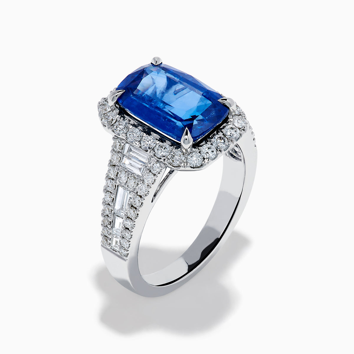 The Effy Hematian 18K Gold Elongated Cushion Blue Sapphire and Diamond Ring features a striking blue sapphire framed by round and baguette diamonds, with additional diamond accents along the split shank band.