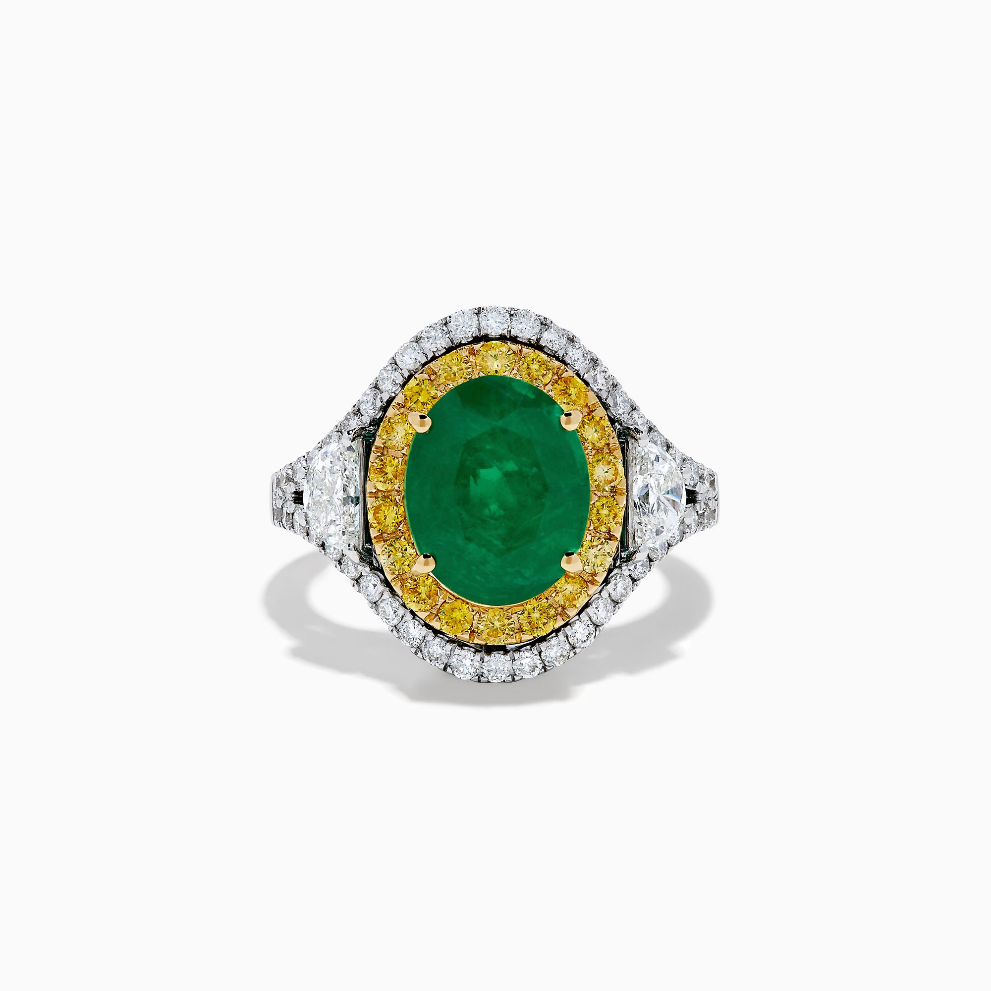 The 18K Gold Emerald, Yellow and White Diamond Double Halo Ring features a large oval green emerald center, surrounded by double halos of yellow and white diamonds with side diamonds on an 18K gold band. Set against a plain white background.
