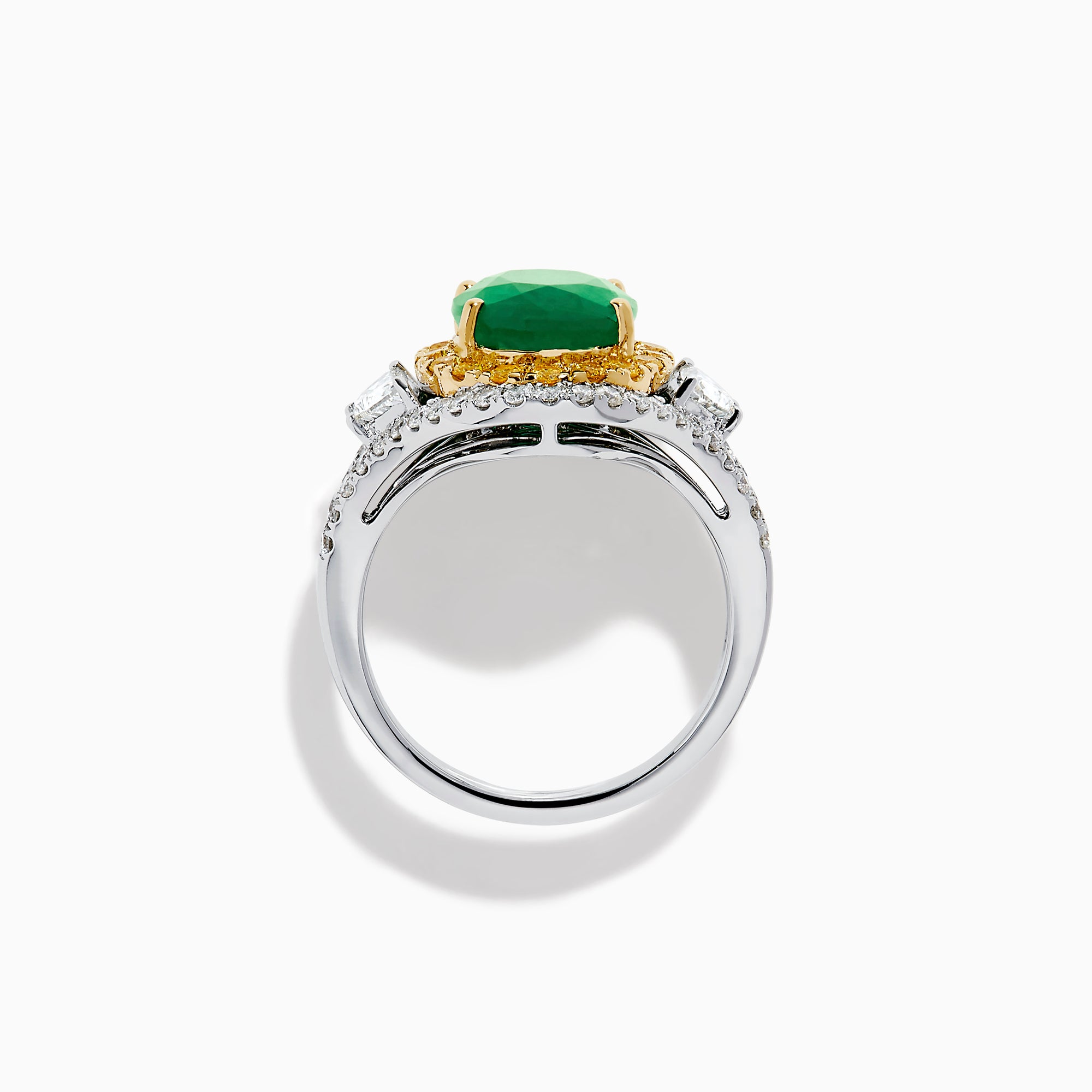 The 18K Gold Emerald, Yellow and White Diamond Double Halo Ring features a large oval green emerald center, surrounded by double halos of yellow and white diamonds with side diamonds on an 18K gold band. Set against a plain white background.
