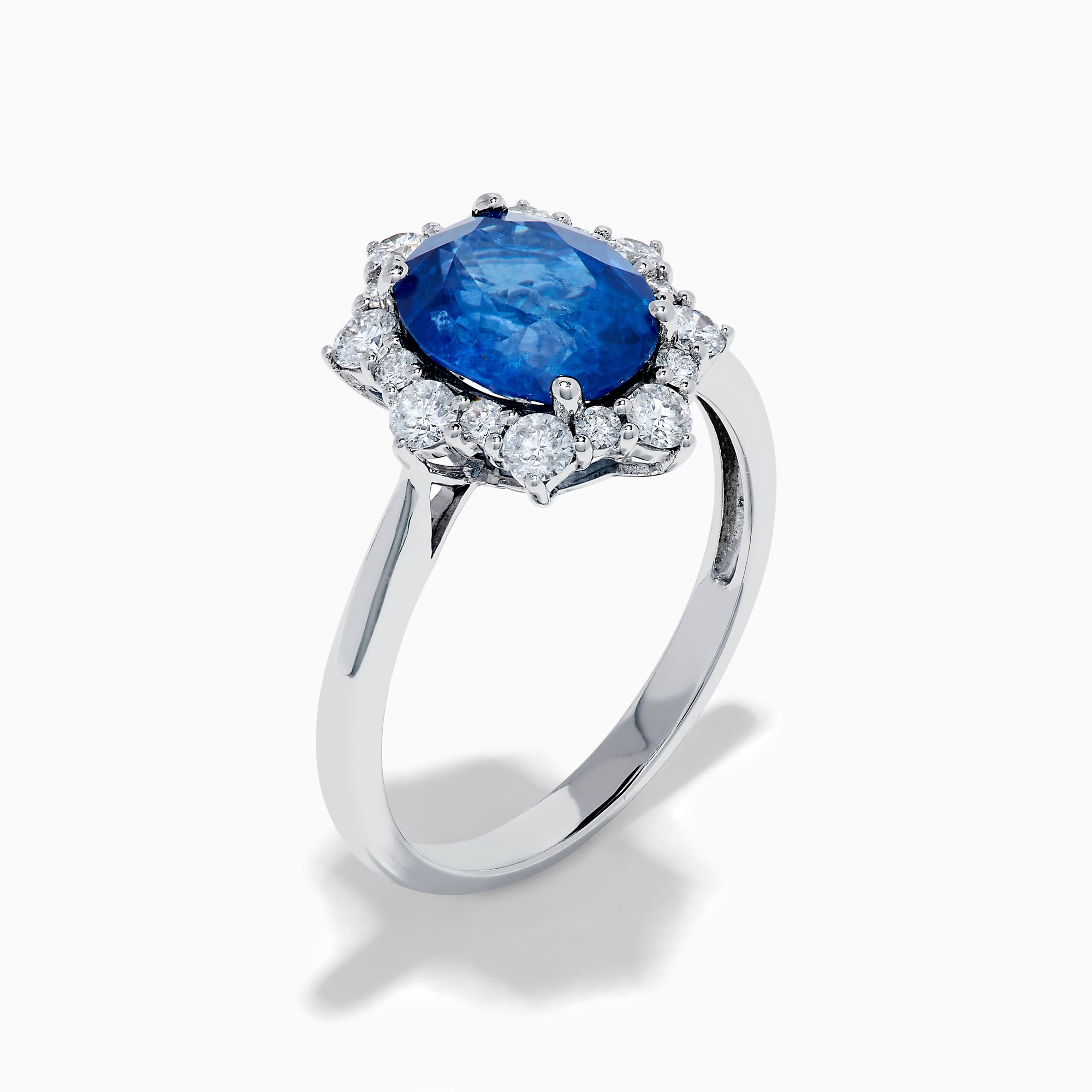 The Effy Hematian 14K White Gold Blue Sapphire and Diamond Halo Ring showcases an oval blue sapphire center, surrounded by a halo of sparkling round white diamonds, presented against a white background.