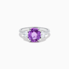 The Effy Hematian 18K White Gold Purple Sapphire and Diamond Three-Stone Ring features a large oval purple sapphire at the center with two smaller diamonds, shown on a white background.