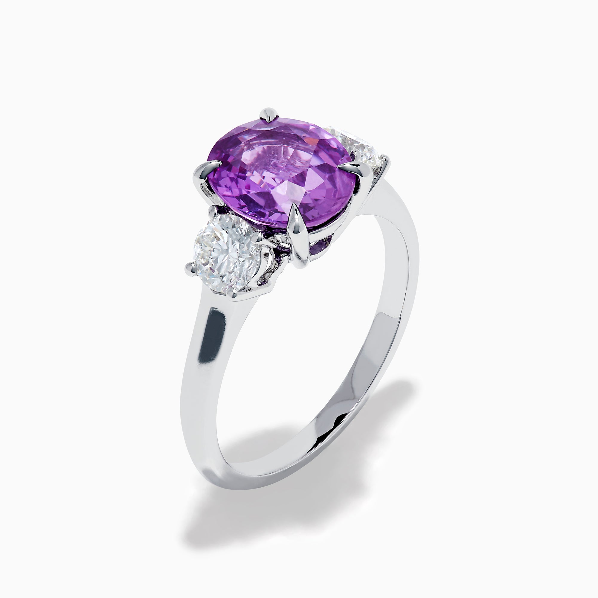 The Effy Hematian 18K White Gold Purple Sapphire and Diamond Three-Stone Ring features a large oval purple sapphire at the center with two smaller diamonds, shown on a white background.