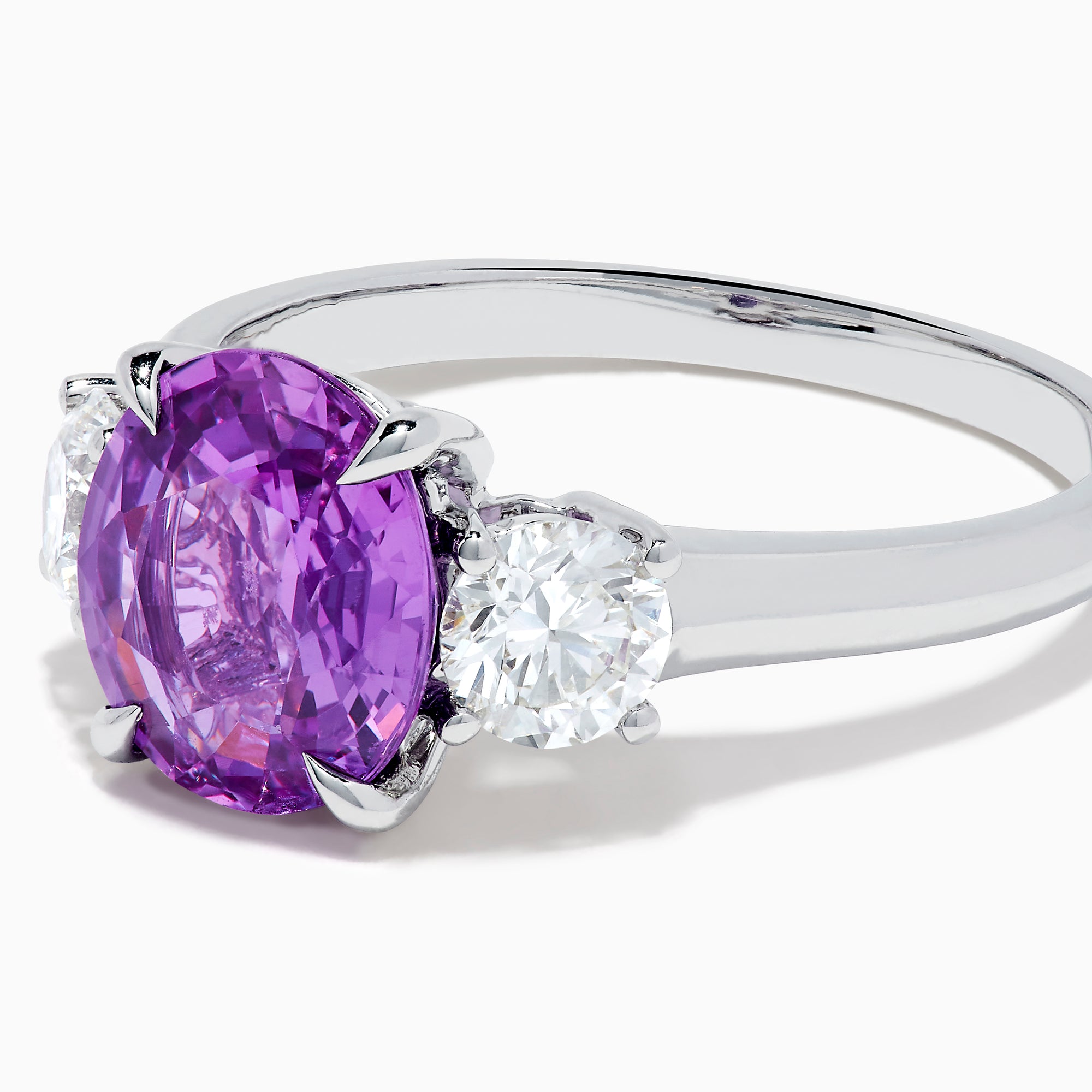 The Effy Hematian 18K White Gold Purple Sapphire and Diamond Three-Stone Ring features a large oval purple sapphire at the center with two smaller diamonds, shown on a white background.