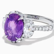 The Effy Hematian 18K White Gold Oval Purple Sapphire and Diamond Halo Ring features a central oval purple sapphire, two oval white diamonds, and smaller diamonds along the band, displayed on a white background.
