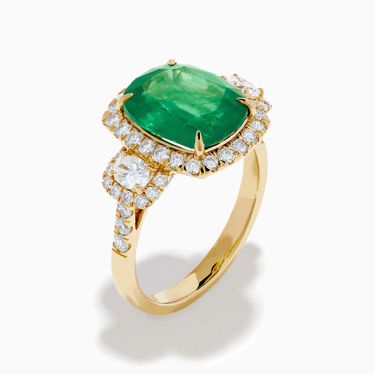 The Effy Hematian 18K Yellow Gold Emerald and Diamond Three Stone Ring features a large cushion-cut emerald, haloed by round white diamonds and accented with diamond clusters for a modern twist on the classic three stone style.