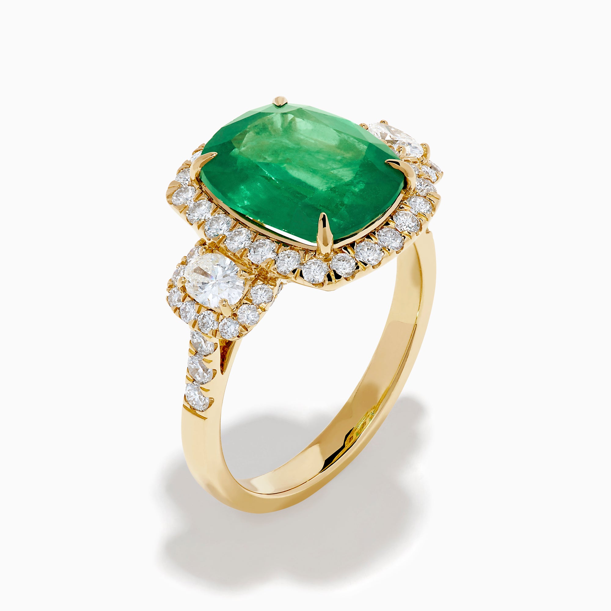 The Effy Hematian 18K Yellow Gold Emerald and Diamond Three Stone Ring features a large cushion-cut emerald, haloed by round white diamonds and accented with diamond clusters for a modern twist on the classic three stone style.
