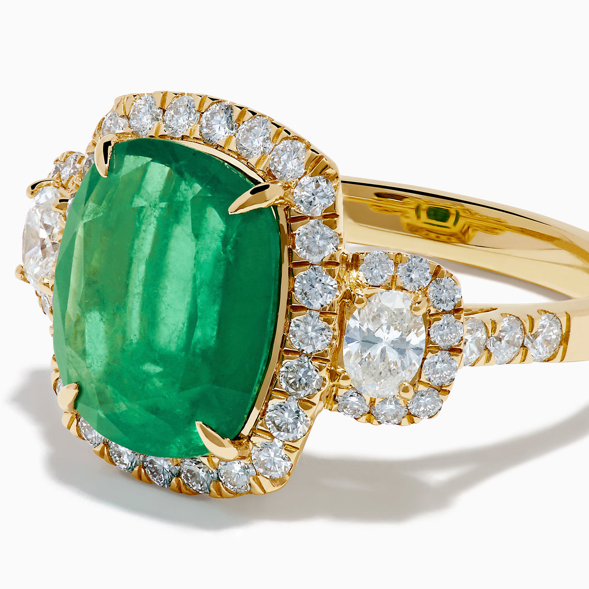 The Effy Hematian 18K Yellow Gold Emerald and Diamond Three Stone Ring features a large cushion-cut emerald, haloed by round white diamonds and accented with diamond clusters for a modern twist on the classic three stone style.