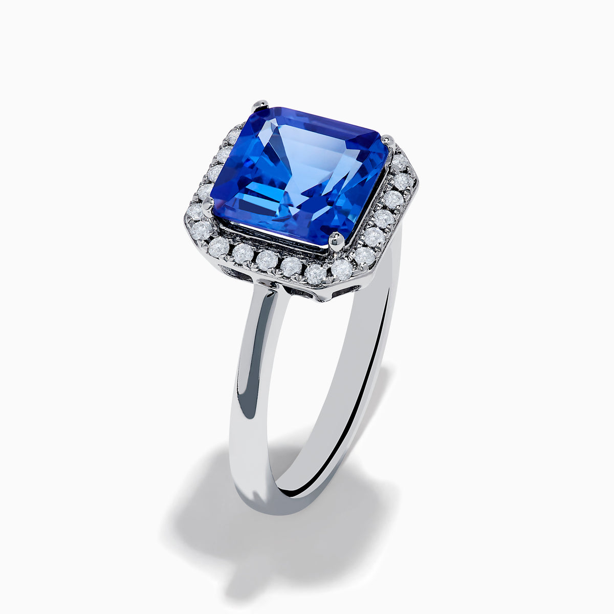 The Nahla Siri 14K Gold Tanzanite and Diamond Ring features a large emerald-cut tanzanite centerpiece, surrounded by a halo of sparkling diamonds, set in elegant gold and showcased against a white background.