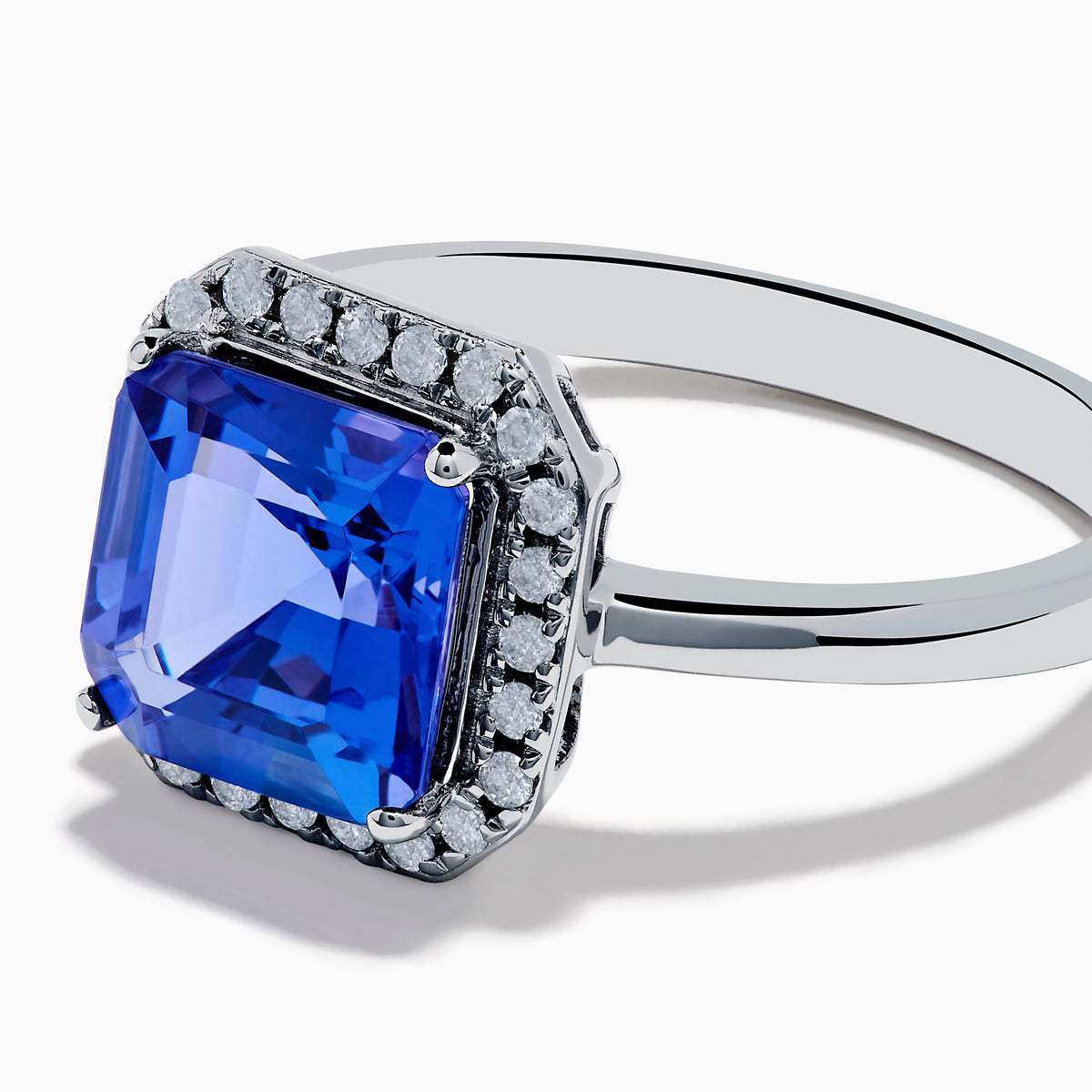 The Nahla Siri 14K Gold Tanzanite and Diamond Ring features a large emerald-cut tanzanite centerpiece, surrounded by a halo of sparkling diamonds, set in elegant gold and showcased against a white background.