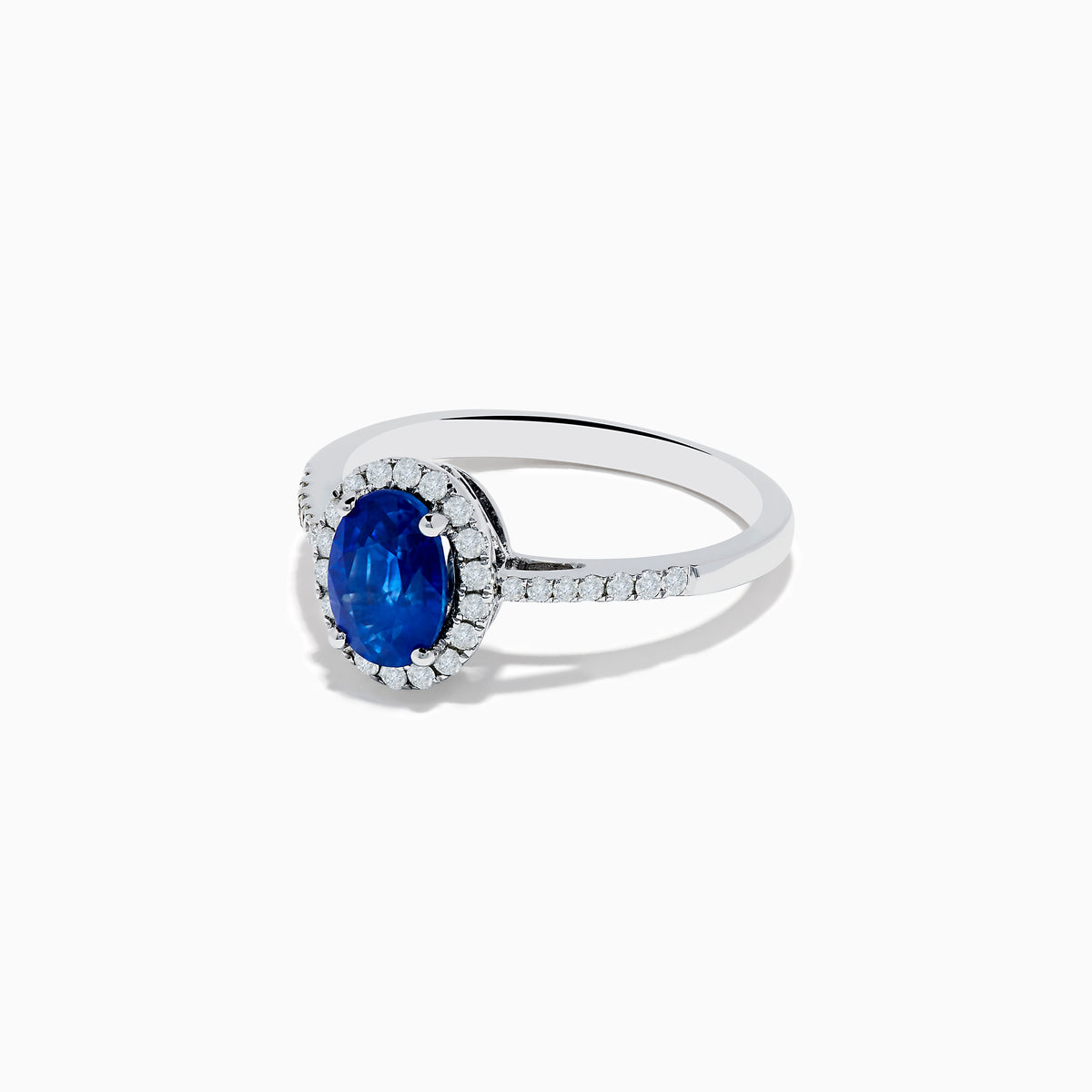 The 14K White Gold Oval Blue Sapphire and Diamond Ring features an oval blue sapphire center, a halo of sparkling diamonds, and additional diamonds set along the band.