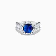 The 18K White Gold GIA Certified Cushion Cut Blue Sapphire and Diamond Ring features a striking cushion cut blue sapphire center, round diamond halo, and baguette-cut diamonds on the band, shown against a white background.