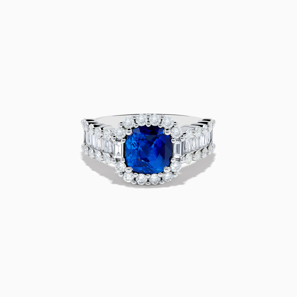 The 18K White Gold GIA Certified Cushion Cut Blue Sapphire and Diamond Ring features a striking cushion cut blue sapphire center, round diamond halo, and baguette-cut diamonds on the band, shown against a white background.