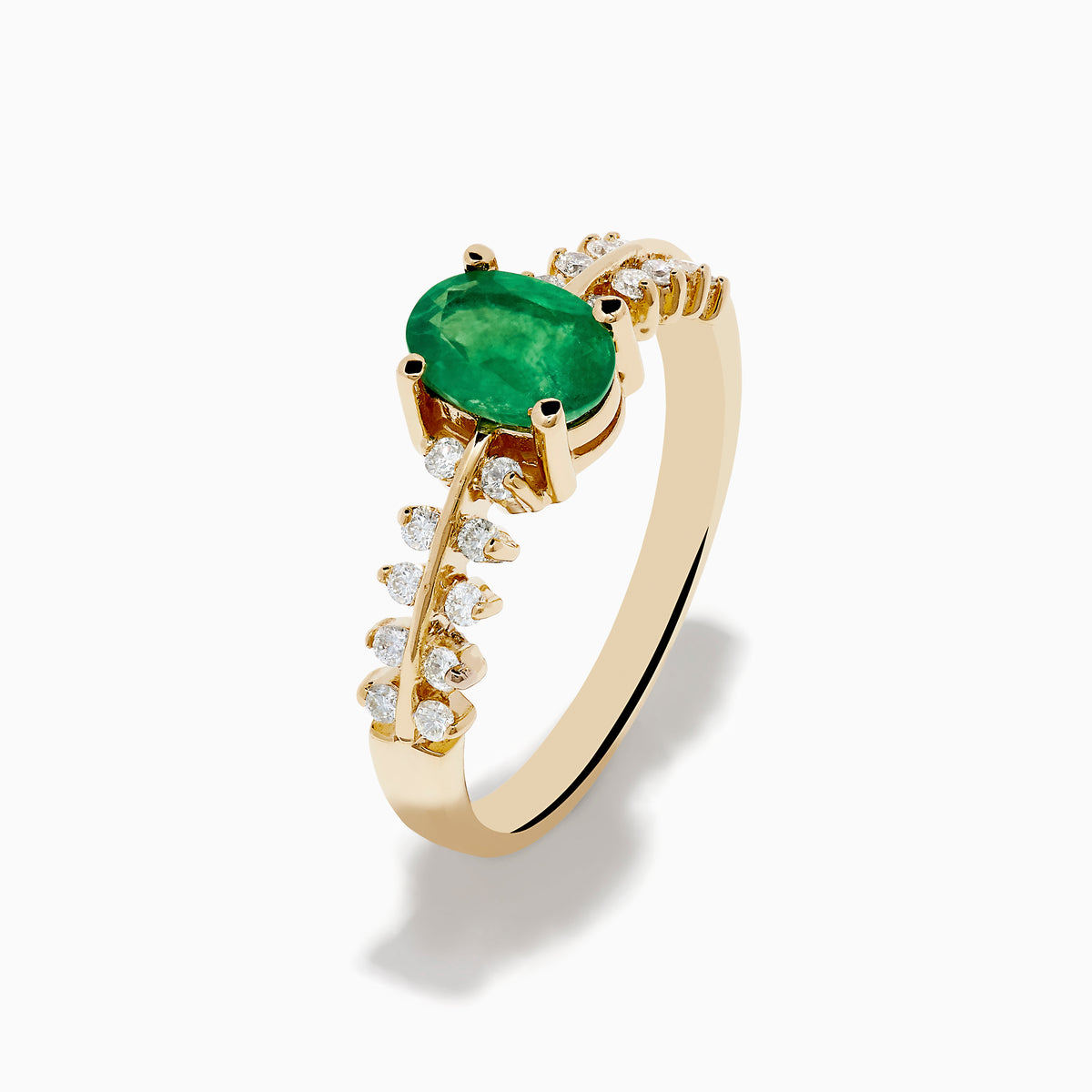The 14K Yellow Gold Emerald and Diamond Ring showcases an oval green emerald center, framed by two rows of round diamonds on each side, set in yellow gold against a white background.