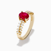 The 14K Yellow Gold Ruby and Diamond Ring features a central oval ruby accented by two rows of small round diamonds on each side, creating a sophisticated and elegant look.