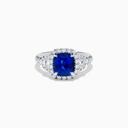 The Royale Bleu Platinum Blue Sapphire Halo Ring showcases a large cushion-cut sapphire surrounded by sparkling diamonds on a platinum band, set against a white background for a timeless, elegant look.
