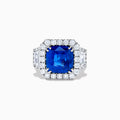 The Royale Bleu 18K White Gold Blue Sapphire and Diamond Halo Ring showcases a cushion-cut blue sapphire center with a double diamond halo and diamond side accents, elegantly set against a white background.