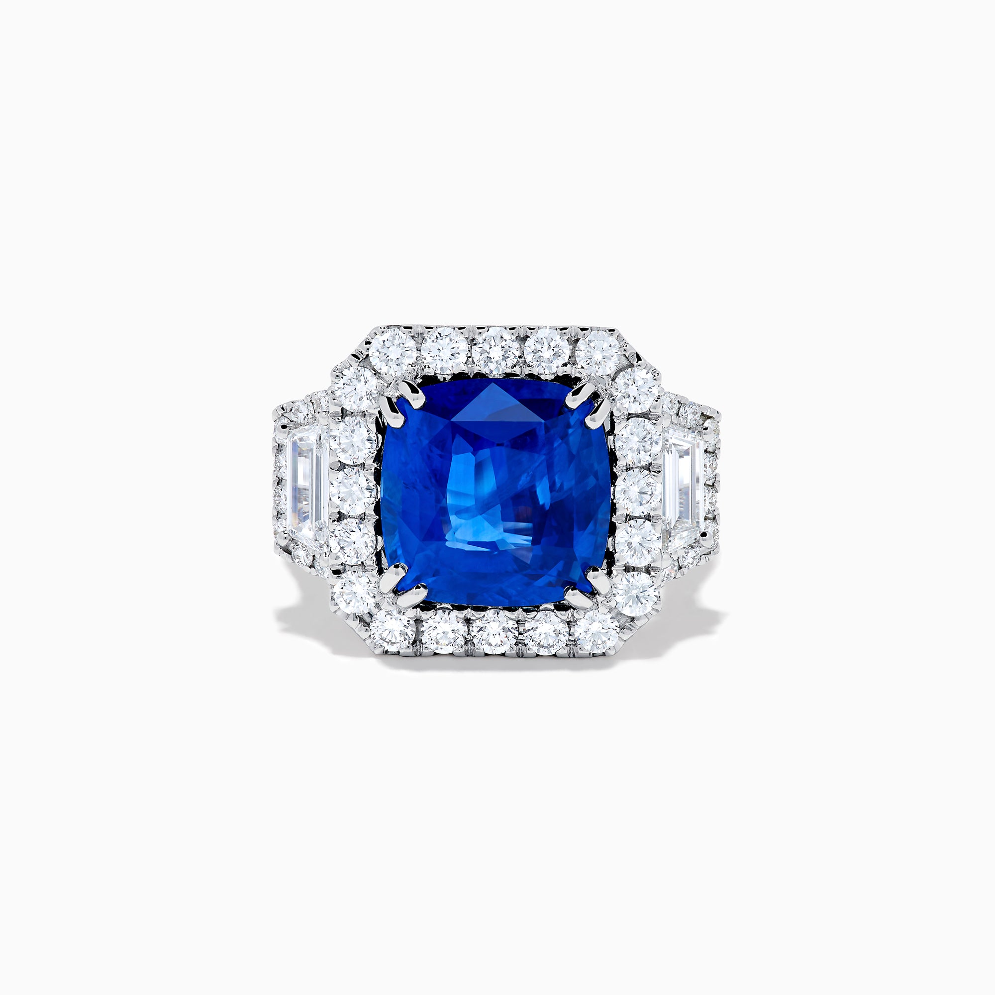 The Royale Bleu 18K White Gold Blue Sapphire and Diamond Halo Ring showcases a cushion-cut blue sapphire center with a double diamond halo and diamond side accents, elegantly set against a white background.