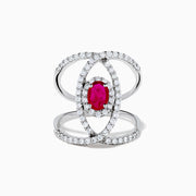 The Ruby Royale 14K White Gold Ruby and Diamond Ring features a central oval ruby with intersecting diamond-encrusted bands, beautifully set against a plain white background.