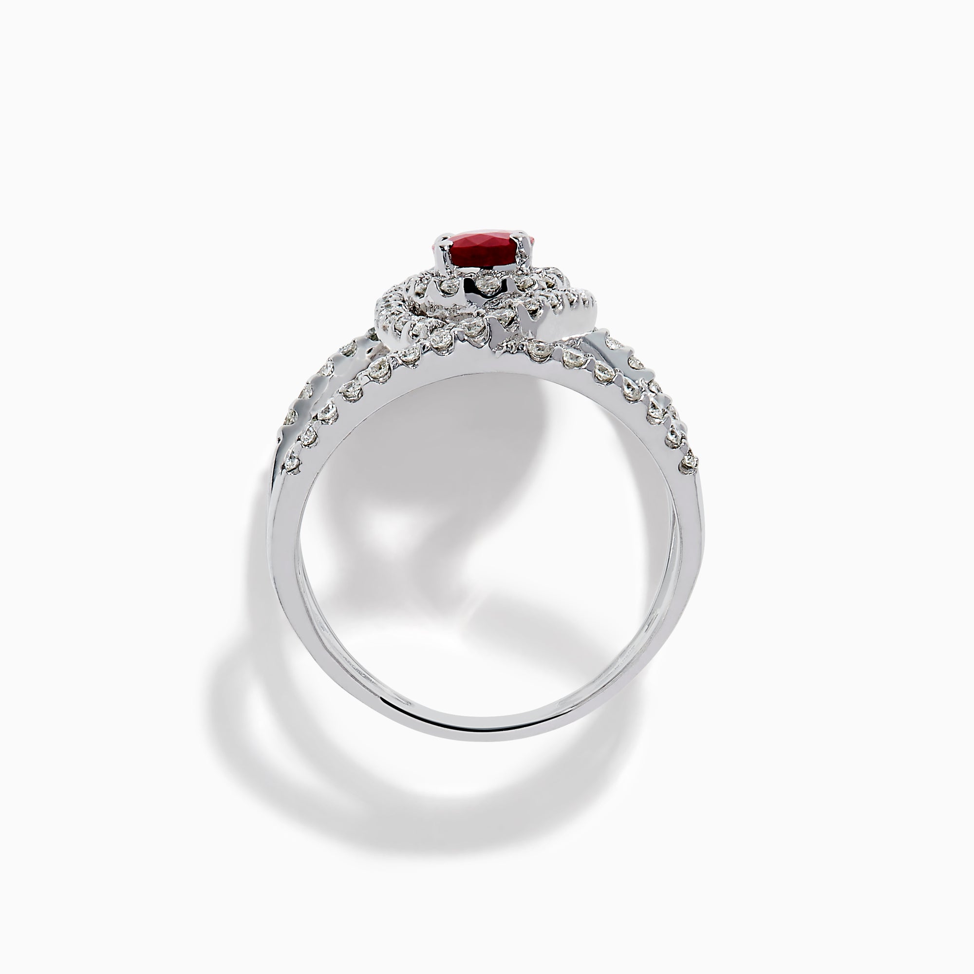 The Ruby Royale 14K White Gold Ruby and Diamond Ring features a central oval ruby with intersecting diamond-encrusted bands, beautifully set against a plain white background.