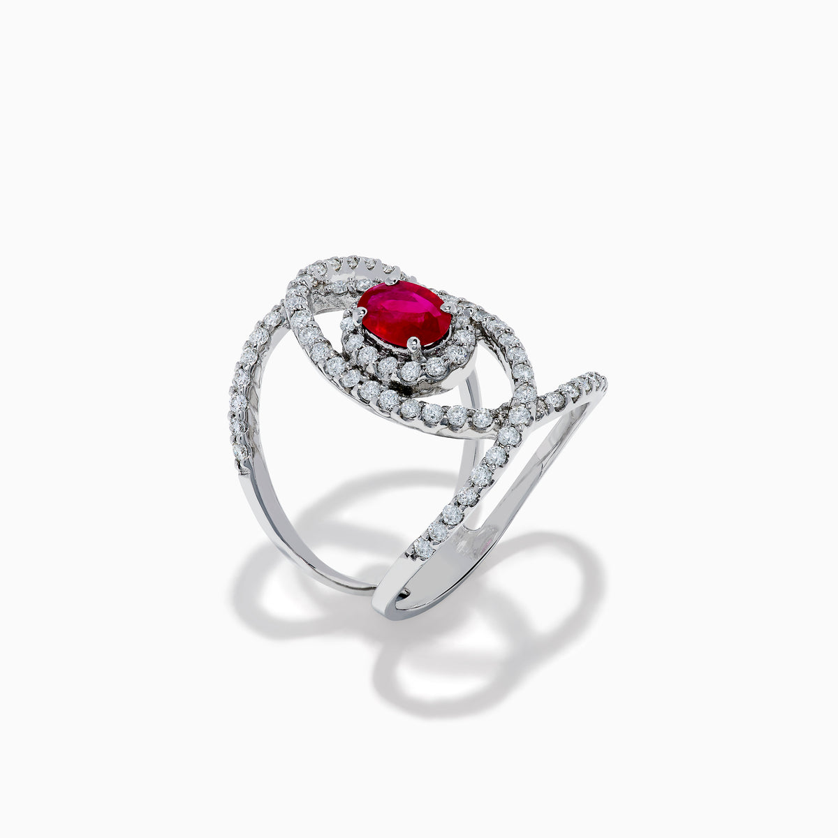 The Ruby Royale 14K White Gold Ruby and Diamond Ring features a central oval ruby with intersecting diamond-encrusted bands, beautifully set against a plain white background.