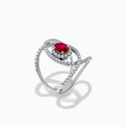 The Ruby Royale 14K White Gold Ruby and Diamond Ring features a central oval ruby with intersecting diamond-encrusted bands, beautifully set against a plain white background.